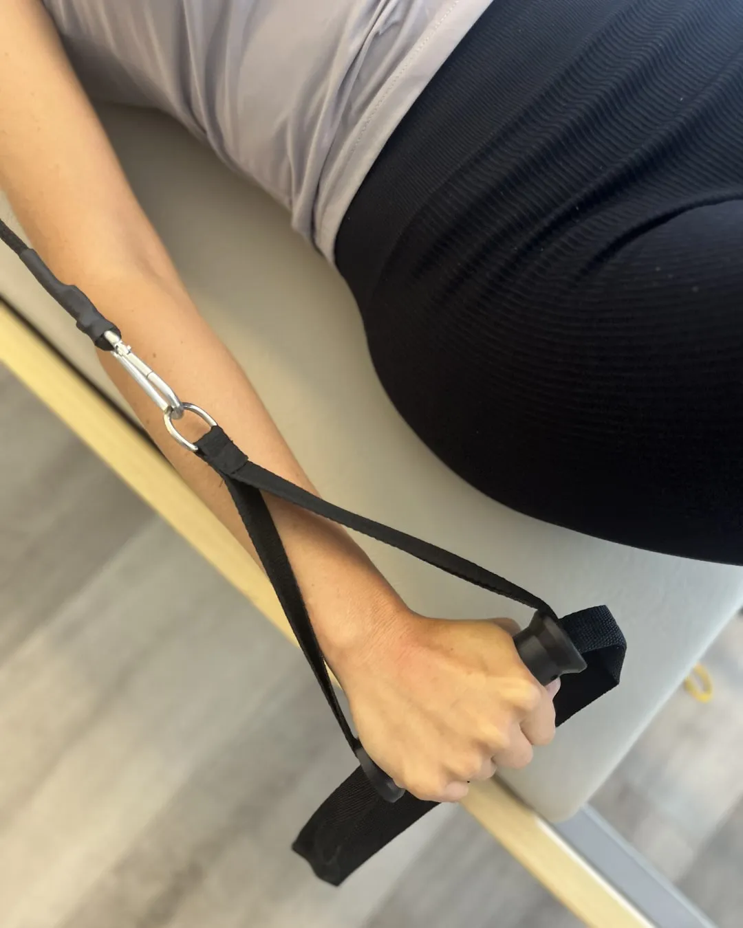 Close-up of a hand holding the reformer strap handle